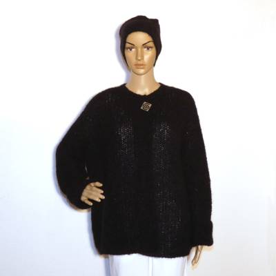 Handgestrickte Damenjacke in schwarz mit Accessoire.