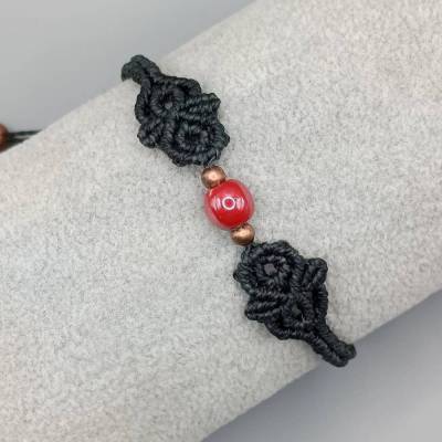 zierliches Makramee Armband in schwarz mit einer roten Keramikperle und kupferfarbenen Metallperlen