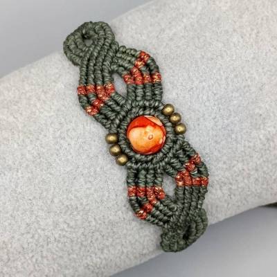 Makramee Armband in olivgrün und metallic orange mit einer marmorierten Acrylperle und bronzefarbenen Metallperl