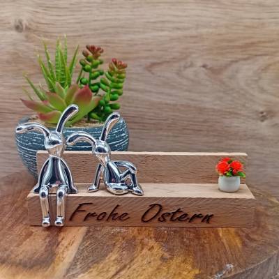 Osterdeko mit 2 silbernen Osterhasen auf einer gravierten Holzbank