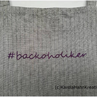 Latzschürze hellgrau #backoholiker, handbestickt, Schriftzug lila, tolle Geschenkidee für Backfeen und HobbybäckerInnen