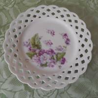 Weißer Teller mit Durchbruchrand und lilafarbenem Blumemmotiv vermutlich aus den 1960ern Jahren Bild 1